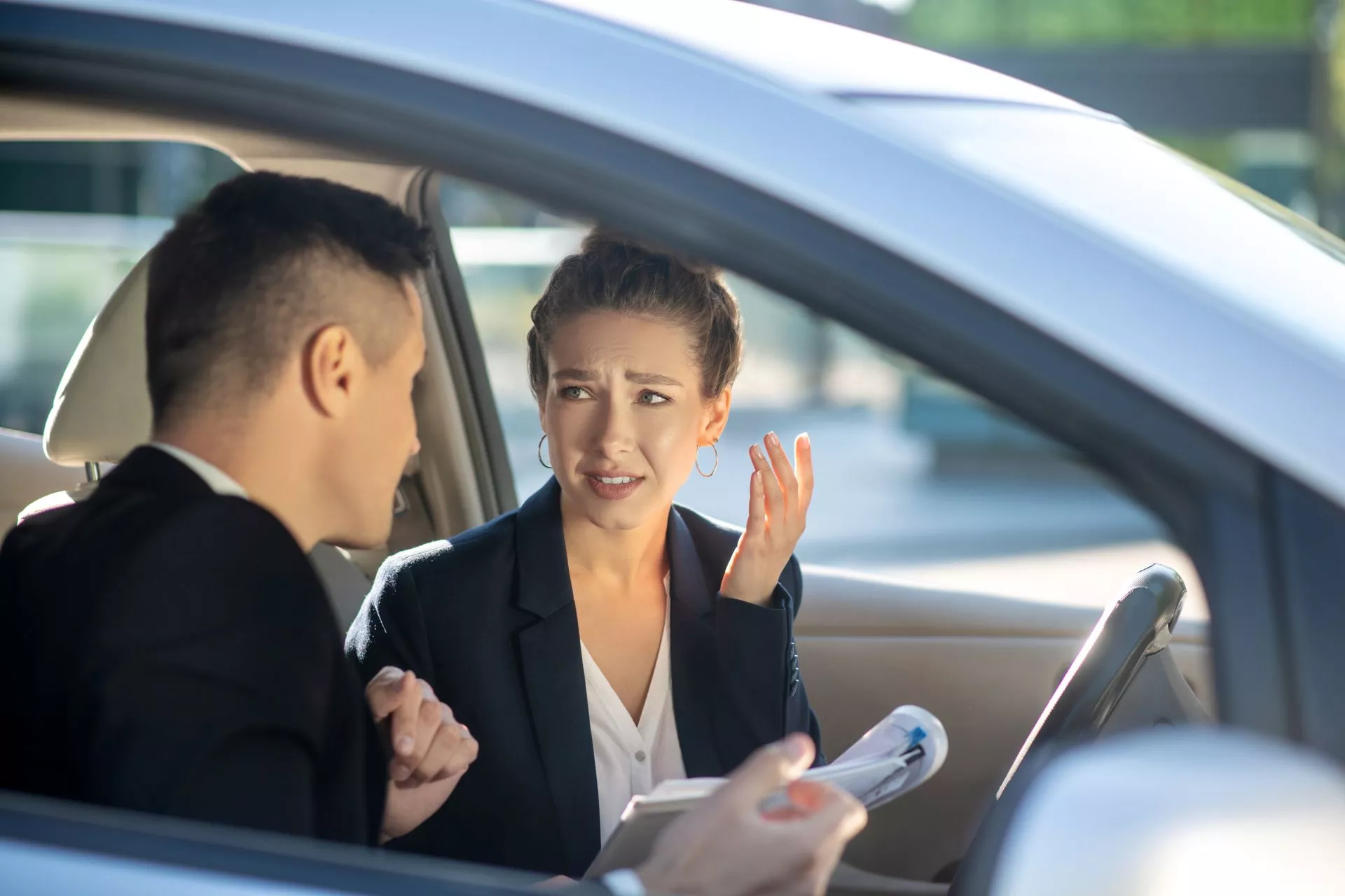 台中當鋪免留車諮詢情境示意圖：男女在車內討論文件與借款流程，呈現汽車借款審核說明與費用確認情境，強調台中當鋪免留車與留車差別與合約細節溝通。